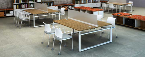 Tayco Concourse workstation featuring a low-profile desk with a sleek, white laminate surface and polished aluminum legs. The desk is surrounded by translucent glass screens that provide privacy without blocking natural light.